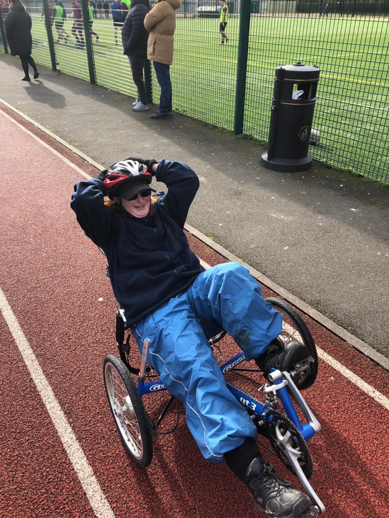 Carlie on recumbent trike - her hands are behind her head. She's smiling and looks very relaxed