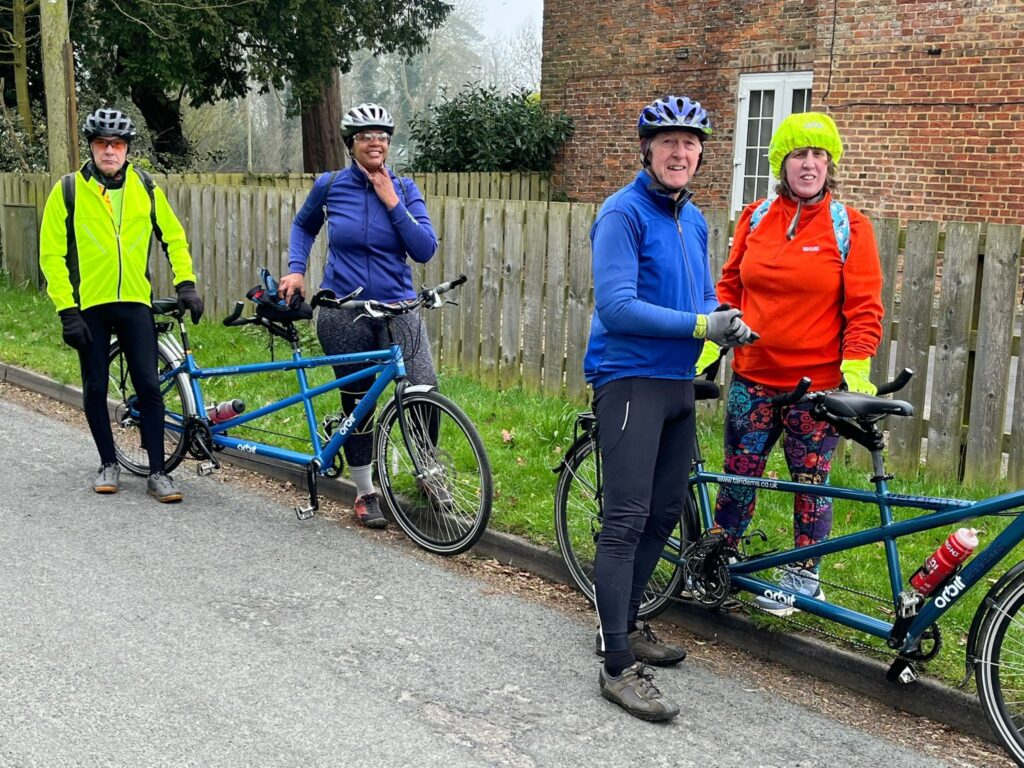 Two tandem crews stood with their bikes leaning beside them, in helmets and light jackets.