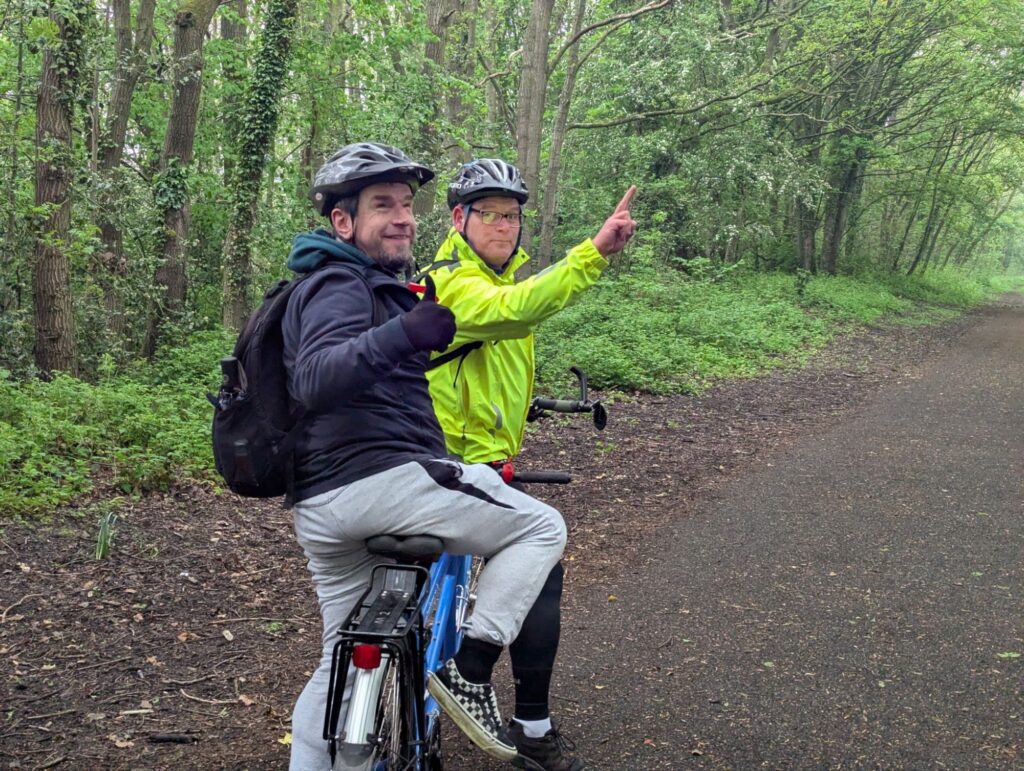 Time ad Bryan on their tandem, stationery, with the pilot pointing ad the stoker giving a thumbs up.
