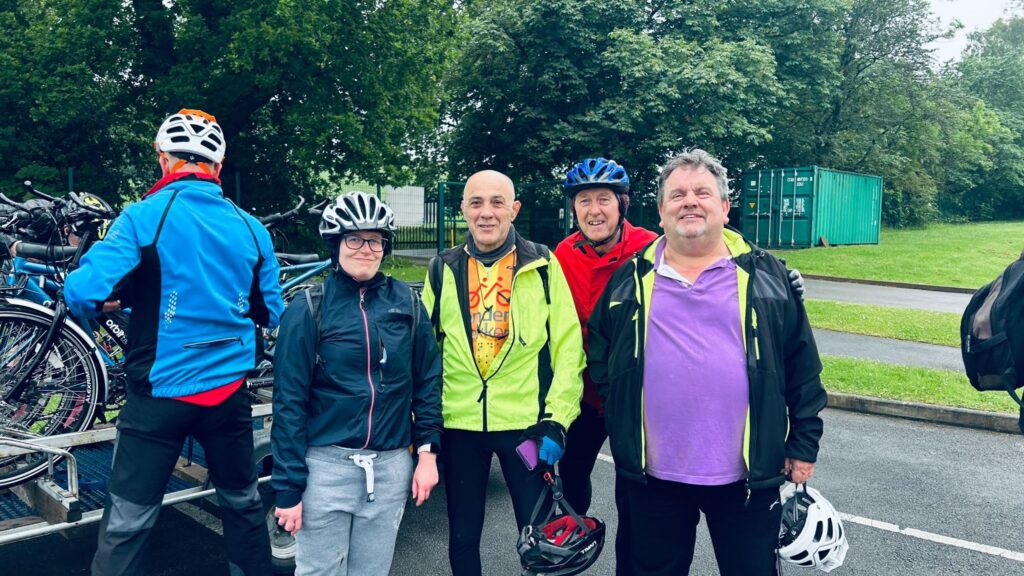 4 regular TT stokers line up, helmets and raincoats on, posing for the camera, smiling.