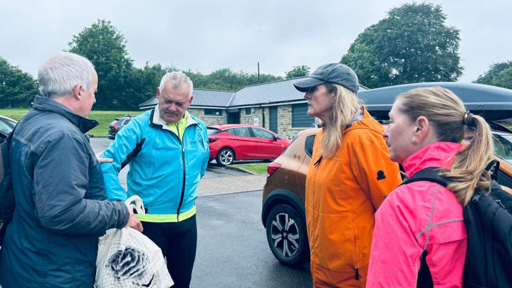 A visually impaired person demonstrates sighted guiding techniques to 3 other people  as part of the TT induction. They are in a circle listening and watching the talk